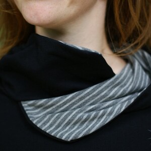 May include: A black mock neck shirt with a striped fabric detail around the neckline.