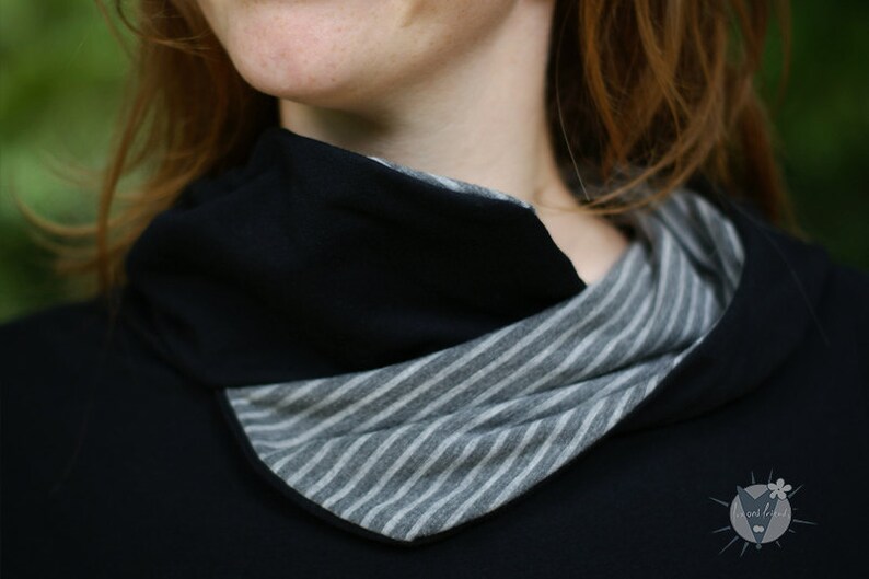 May include: A black mock neck shirt with a striped fabric detail around the neckline.