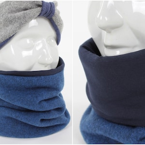 May include: A blue fleece neck warmer with a dark blue fleece lining. The neck warmer is folded and displayed on a white mannequin head.