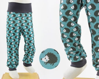 Op de afbeelding: Tealblauwe kinderleggings met een herhalend patroon van zwarte en witte egels. De leggings hebben een donkergrijze tailleband en boorden.