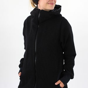 May include: A black zip-up jacket with a high collar and a black and white patterned lining. The jacket has a relaxed fit and is made of a soft, comfortable fabric.