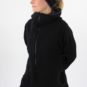 May include: A black zip-up jacket with a high collar and a unique cut-out detail on the side. The jacket is made of a soft, textured fabric.