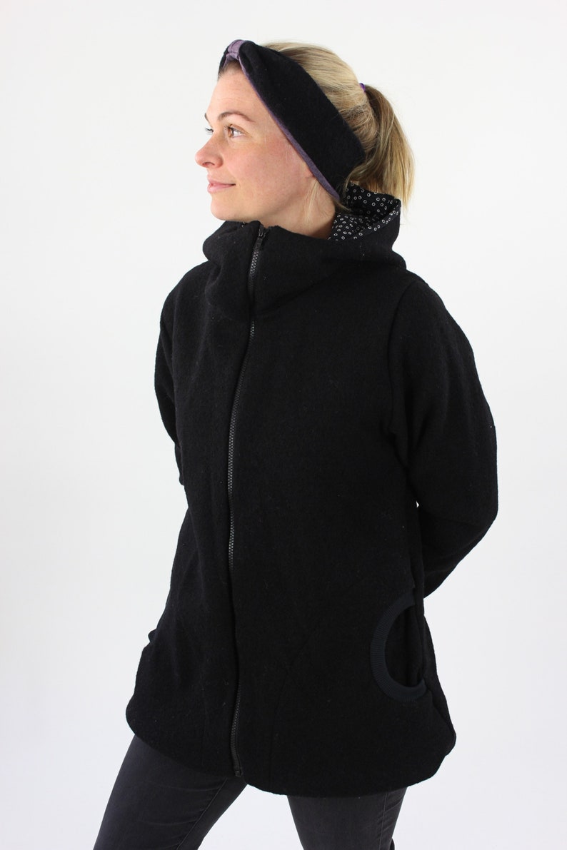 May include: A black zip-up jacket with a high collar and a unique cut-out detail on the side. The jacket is made of a soft, textured fabric.