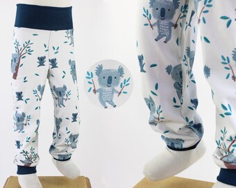 Op de afbeelding: Witte katoenen broek met een blauwe tailleband en een herhalend patroon van grijze koala's die takken vasthouden. De koala's worden omringd door kleine groene bladeren.