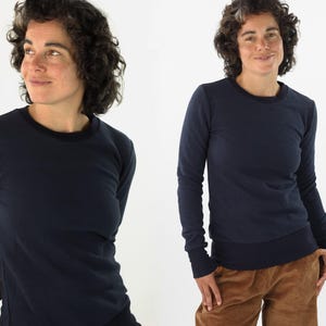 Könnte beinhalten: Marineblaues Langarmshirt mit Rundhalsausschnitt und gerippten Bündchen. Das Shirt besteht aus einem weichen, bequemen Material. Das Model trägt eine braune Cordhose. Ein vielseitiges Kleidungsstück für den Freizeitgebrauch.