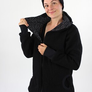 May include: A black zip-up jacket with a black and white patterned lining. The jacket has a hood and a large pocket on the side.
