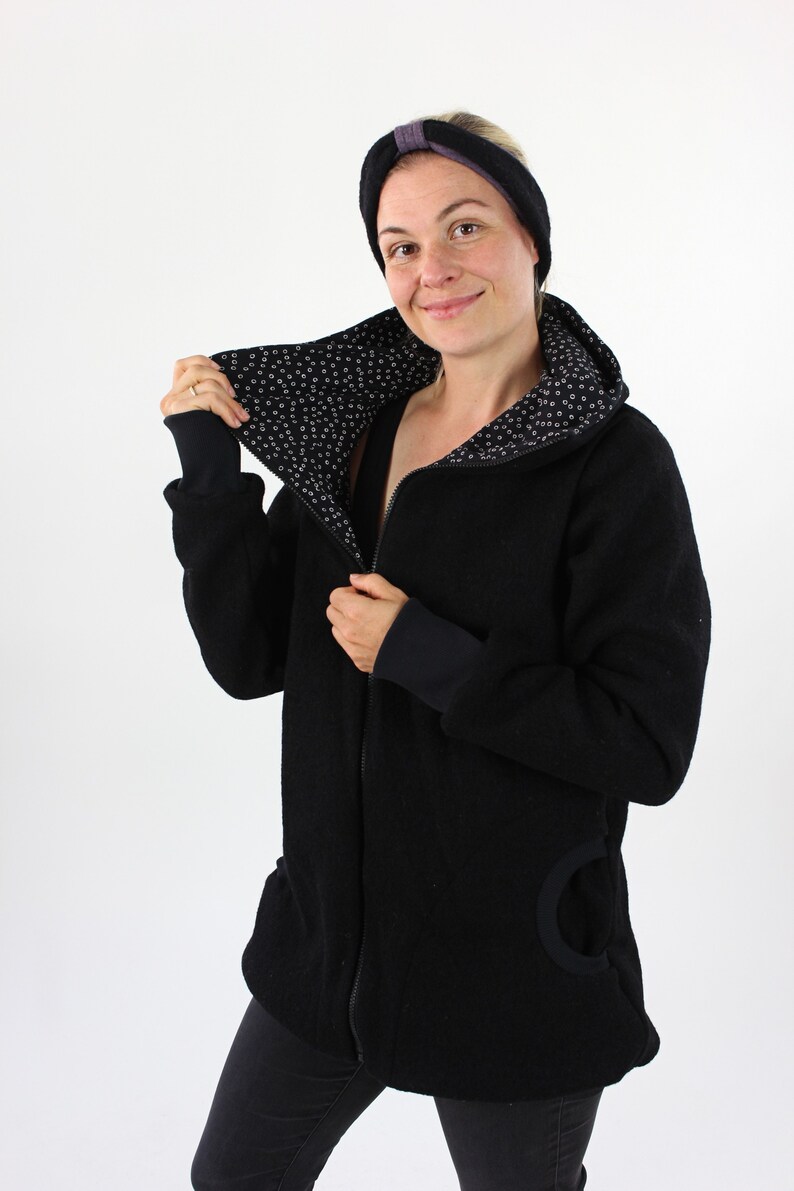 May include: A black zip-up jacket with a black and white patterned lining. The jacket has a hood and a large pocket on the side.