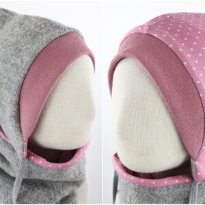 May include: Gray hooded scarf with a pink polka dot trim. The hood has a pink lining.