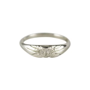 Op de afbeelding: Een zilveren ring met een gedetailleerd ontwerp van twee vleugels aan de bovenkant.
