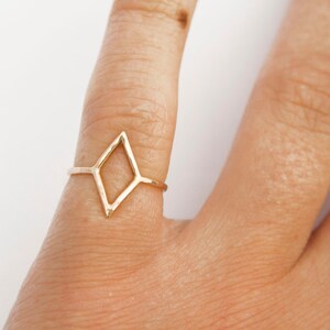 Very thin wire creating the outline of a diamond shape with thin wire as the ring band. Shown in gold tone with a light hammered finish worn as a pinky ring.