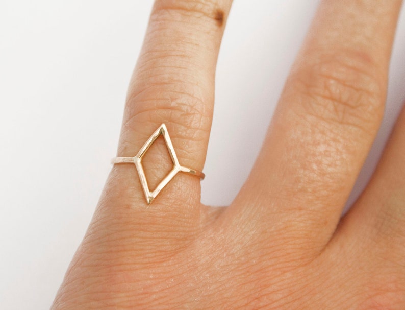 Very thin wire creating the outline of a diamond shape with thin wire as the ring band. Shown in gold tone with a light hammered finish worn as a pinky ring.