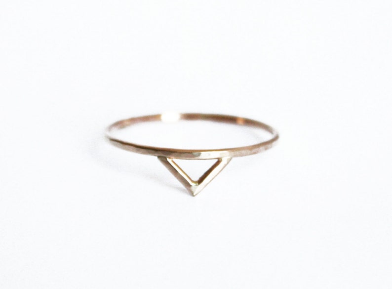 Thin gold ring with the outline of a triangle or a spike shape on one side of the ring. Slight hammered texture.