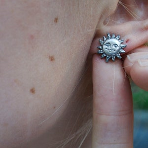 Sun earring being shown worn on a models ear.