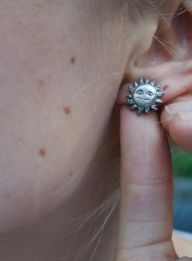 Sun earring being shown worn on a models ear.