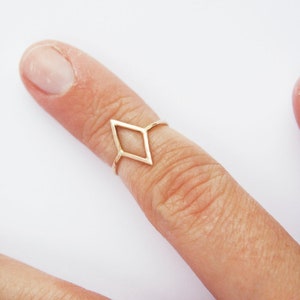 Very thin wire creating the outline of a diamond shape with thin wire as the ring band. Shown in gold tone with a light hammered finish worn as a midi ring on the top of a pointer finger.