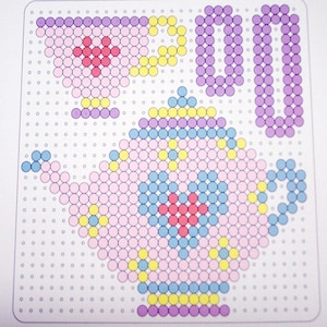 May include: A bead pattern for a teapot and teacup. The pattern is made up of pink, yellow, blue, and red beads. The teapot is in the centre of the pattern and the teacup is to the left.