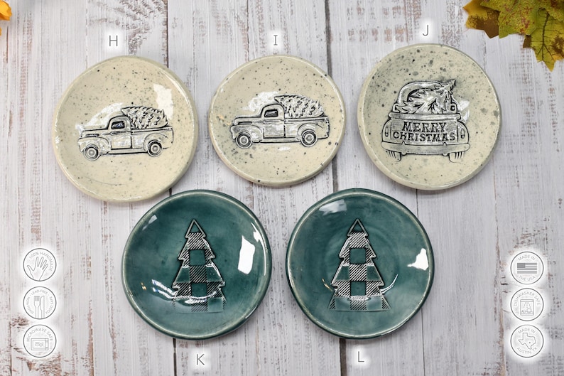 May include: A collection of small, round ceramic plates with Christmas-themed designs. Some plates feature a truck carrying a Christmas tree, while others display a plaid Christmas tree. The plates are in various colors.