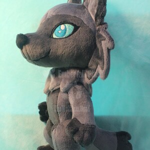 May include: A gray plush wolf with blue eyes and a white nose. The wolf is standing on a light blue surface.