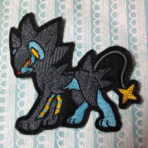 May include: Embroidered patch of a black and blue Pokemon character with a yellow star on its tail.