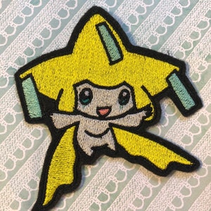 May include: Embroidered patch of a yellow and white Pokemon character with a star-shaped head and a light blue face. The character has a big smile and is wearing a yellow and white outfit.
