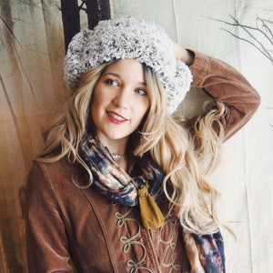 May include: A woman wearing a brown corduroy jacket with a white fur trim, a gray fuzzy hat, and a scarf with a floral pattern.