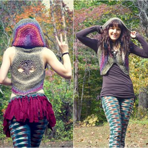 May include: A woman wearing a crocheted vest with a tree design on the back. The vest has a hood and is made with a rainbow of colors. She is also wearing a long-sleeved shirt, leggings, and a crocheted hat.