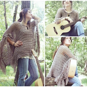 K&ouml;nnte beinhalten: Eine Frau tr&auml;gt einen braunen H&auml;kelponcho mit Fransen, blaue Jeans und ein wei&szlig;es Spitzenoberteil. Sie h&auml;lt eine Gitarre und steht in einem Wald.