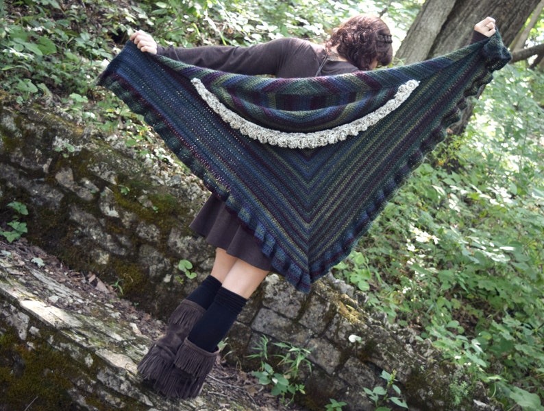 May include: A dark green, blue, and purple crocheted shawl with a white crocheted trim. The shawl has a scalloped edge and a pointed shape.