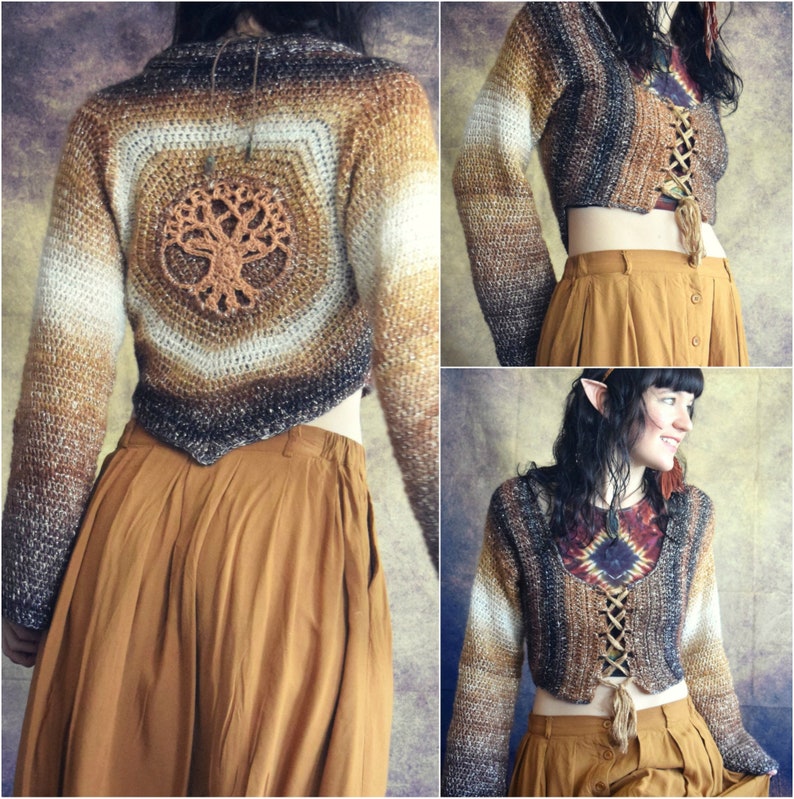 May include: A brown and white crocheted cropped sweater with a tree design on the back. The sweater has a lace-up detail in the front. The model is wearing a brown skirt.