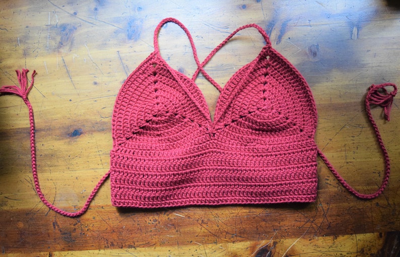 May include: A red crocheted halter top with a criss-cross back and long ties.