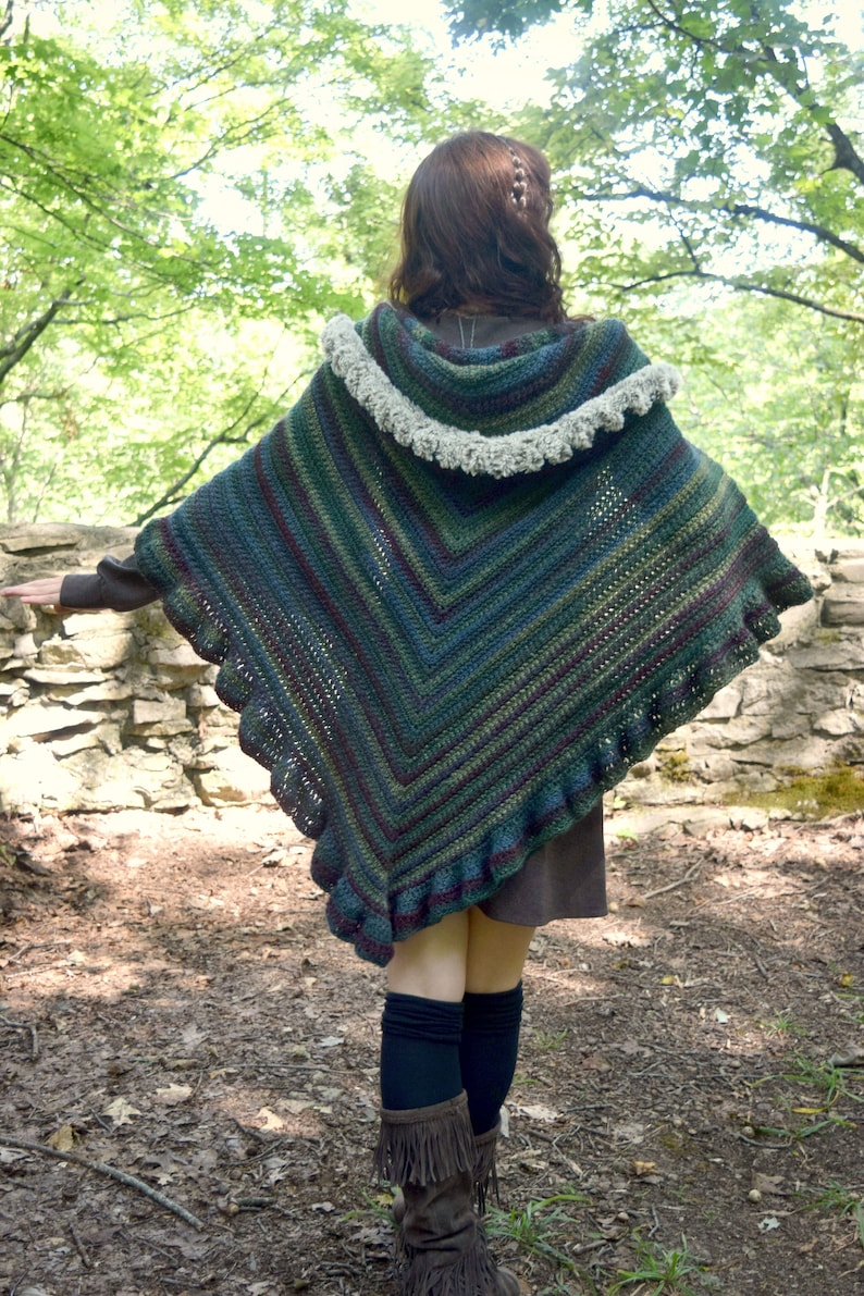 Puede incluir: Un chal de ganchillo con cuello con capucha y borde rizado. El chal est&aacute; hecho en una variedad de tonos de verde, azul y morado.