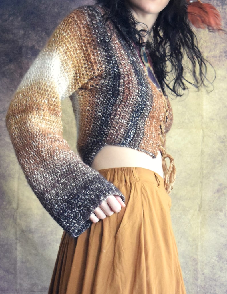 May include: A brown, white, and black ombre knit sweater with a lace-up front and long sleeves. The sweater is cropped and has a relaxed fit.