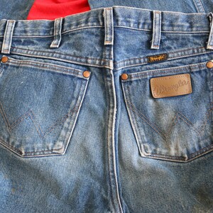 May include: A pair of blue denim jeans with a brown leather patch that says "Wrangler" on the back pocket.