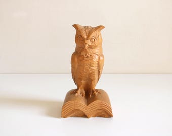 本の上に立つ真鍮製のフクロウの置物、緑のフェルト製の台座付き