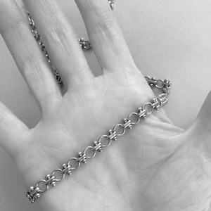 May include: A silver chain necklace with a delicate, linked design. The chain is made of small, round links with a slightly textured surface.