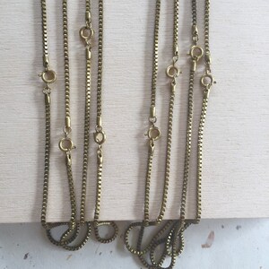 May include: Five gold-toned chain necklaces with lobster claw clasps. The chains are all the same style, but different lengths.