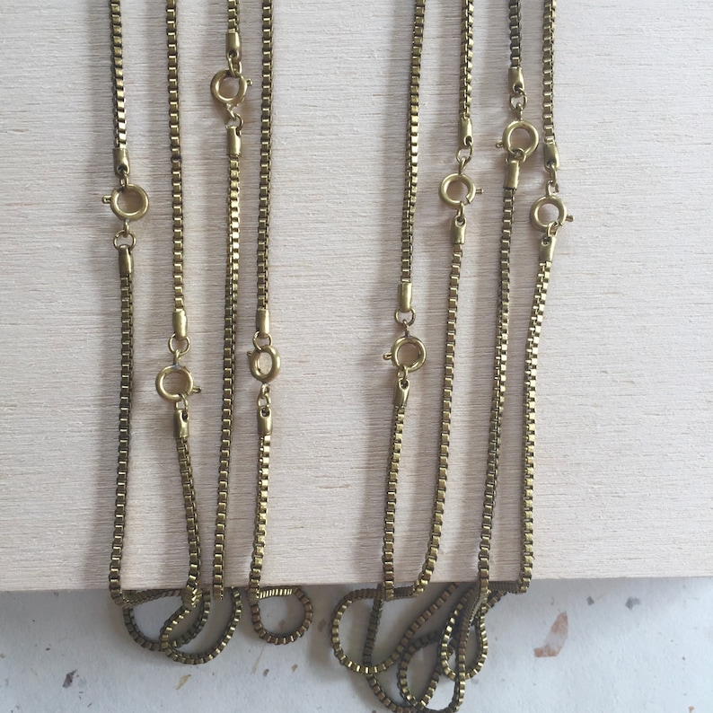 May include: Five gold-toned chain necklaces with lobster claw clasps. The chains are all the same style, but different lengths.