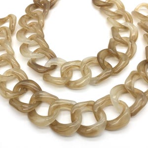May include: A necklace composed of large, interlocking oval links made from a translucent, marbled beige and taupe resin material. The chain features a smooth, glossy finish with swirling color patterns throughout each individual link.