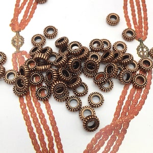 May include: A large pile of antique gold-toned metal beads with a textured surface. The beads are round and have a hole in the center.