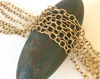 May include: A close-up of a gold chain, wrapped around a textured, green and brown oval-shaped object. The chain is made of oval-shaped links.