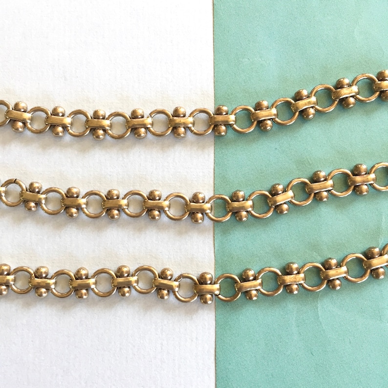 May include: Three rows of silver chain with small round beads. The chain is made of interlocking circles with a bead in the center of each circle.