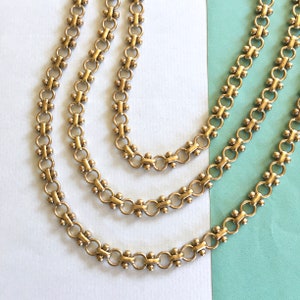 May include: Three gold chains with a linked pattern. Each link has a small round bead in the center.