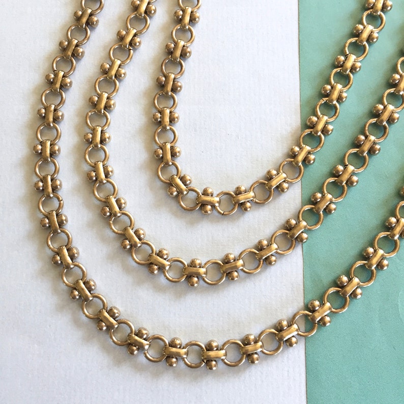 May include: Three gold chains with a linked pattern. Each chain has a different length.