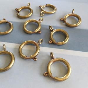 May include: Ten gold-toned metal ring clasps with a spring closure. The clasps are approximately 1 inch in diameter.