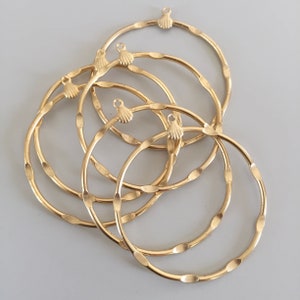 May include: Five gold-colored metal hoops with a decorative seashell charm at the top of each hoop.