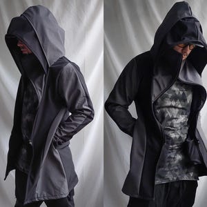 May include: A dark gray hooded coat with a unique asymmetrical design. The coat features a large hood, a draped front, and a contrasting gray panel on the sleeves. The inner shirt has a geometric pattern. The coat is made of a soft, flowing material.