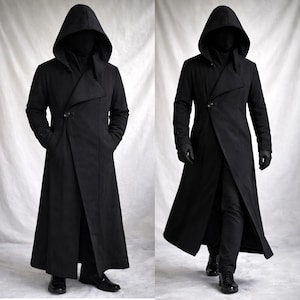 Può includere: Due immagini di un lungo cappotto nero con cappuccio. Il cappotto ha una chiusura asimmetrica con un solo bottone. Il cappotto, lungo fino al pavimento, ha un design drammatico e fluido. Il modello indossa guanti neri e scarpe nere.