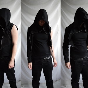 May include: A black hooded jacket with a zip fastening and long sleeves. The jacket is cropped and has a slouchy fit. The model is wearing black trousers and a black shirt.