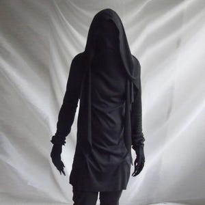May include: A long-sleeved black tunic featuring an attached hood that drapes over the head and shoulders. The garment has a smooth, solid black fabric construction with fitted sleeves and a straight hemline that falls below the waist.