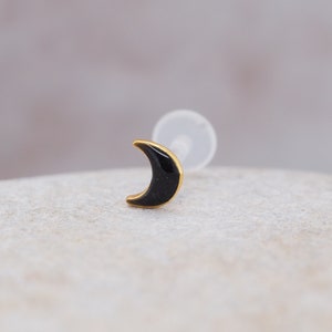 Könnte beinhalten: Ein goldener Halbmond-Ohrring mit schwarzer Emaille-Füllung.